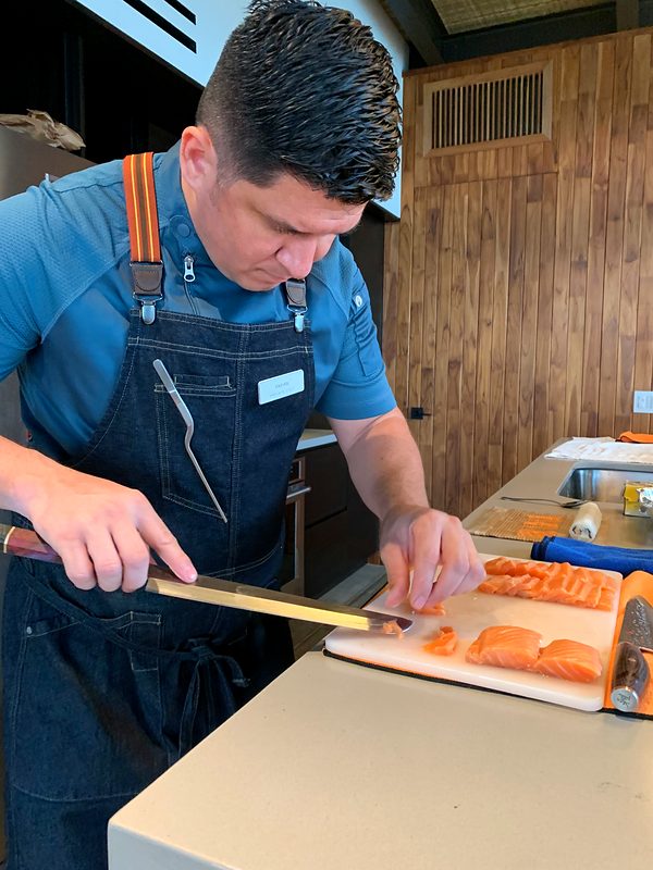 Chef Fabián Argüello slicing salmon in the kitchen of a villa in Guanacaste