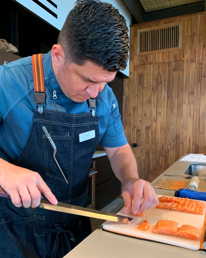 Chef Fabián Argüello slicing salmon in the kitchen of a villa in Guanacaste